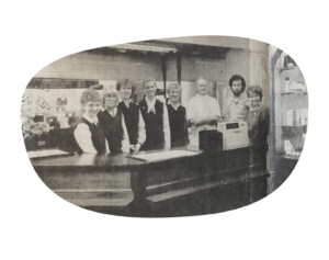 Bilde fra 1967 av de ansatte i butikken bak disken